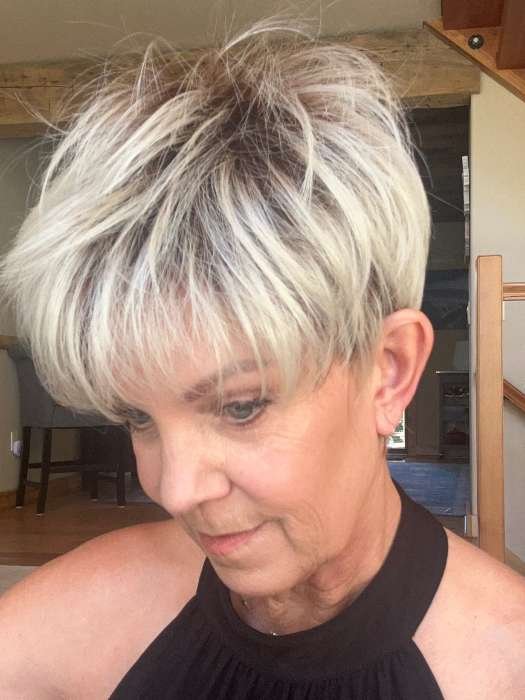 short blonde synthetic wig on mature woman in layered pixie cut with dark roots and bangs