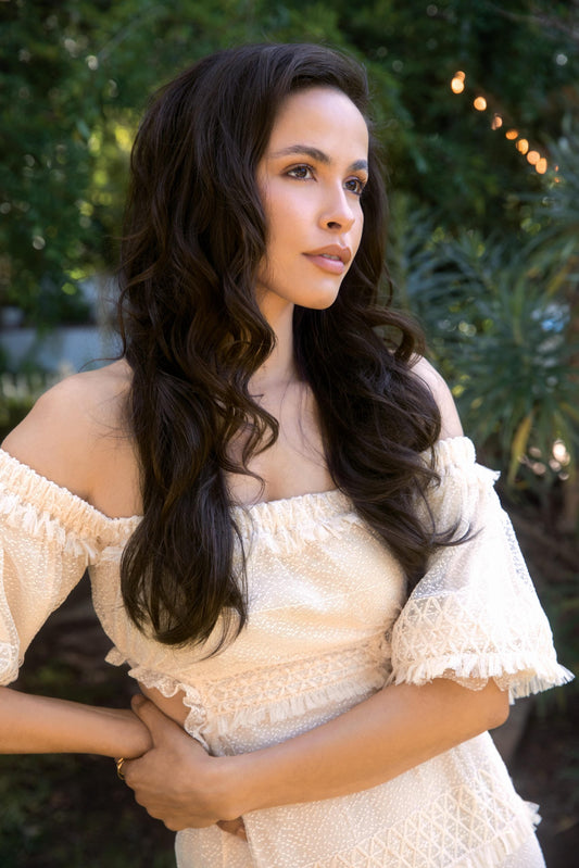 Model wearing layered dark brown wig for women with long soft waves and natural hairline in outdoor boho style